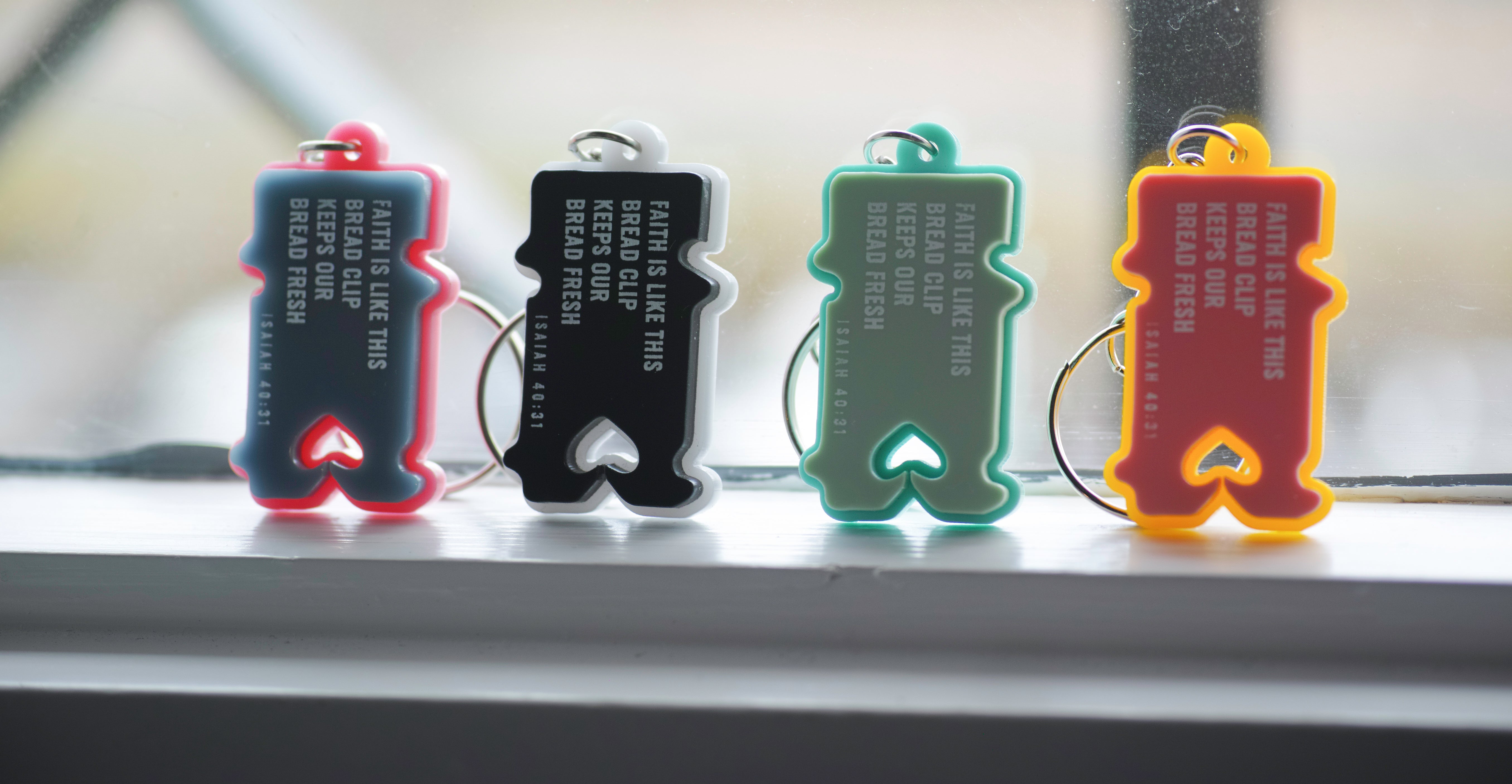 Four colorful keychains with text on a reflective surface